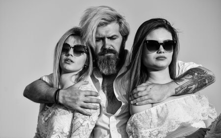 Summer holidays. Relations friendship romance. Threesome concept. In love with both. Friends at rooftop party. Stylish hipster and women white clothes. Women and man friends cuddling. Familyの写真素材