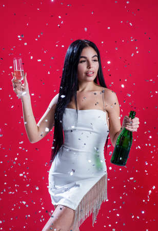 sexy woman drinking champagne from glass under falling confetti, anniversaryの写真素材