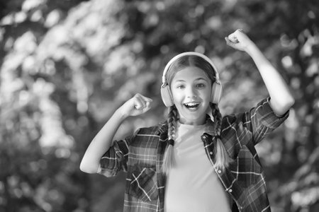 Exclusive holidays for winner. Happy child make winner gesture. Small winner celebrate to music natural outdoors. Celebrating winning. Casual fashion. Trendy style. Summer vacationの写真素材