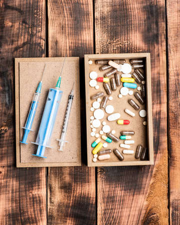 Pharmaceutical drugs pills and syringe vials in box on wooden background, first aid kitの写真素材