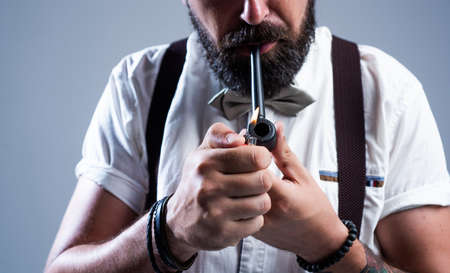 brutal bearded male with stylish look smoking pipe, smokerの写真素材
