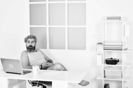 Handsome man using laptop at home. self quarantine routine. Serene barefoot guy resting, daydreaming at home. remote workday with computer. networking while staying at home. Technologyの写真素材