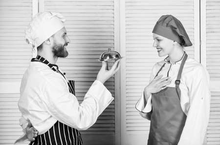 Delicious proposal. Join gourmet lifestyle. Man chef offer dessert or meal under cloche to girl. Will you eat my meal. Culinary family. Woman and bearded man cooking together. Cooking exclusive mealの写真素材