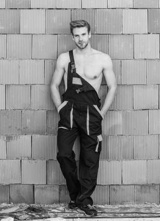 Building construction. Man build own house. Handsome sexy laborer. Attractive worker. Inspecting building. General maintenance repair worker fix maintain building. Worker brick wall backgroundの写真素材