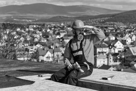 Roofer constructing roof. Master repair roof. Flat roof installation. Man hard hat working outdoor...