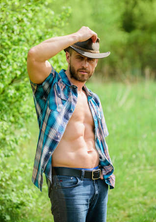 Guy bearded cowboy in nature. Macho six packs torso wear rustic style clothes and cowboy hat. Strong and confident cowboy. Owner of rancho. Man unshaven face muscular torso cowboy. Farm conceptの写真素材