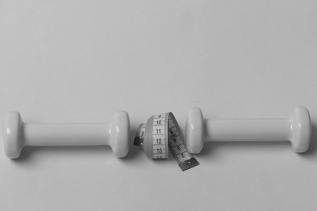Dumbbells made of plastic and measure tape on cyan backgroundの写真素材