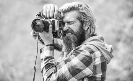 Enjoying hot day. bearded man hipster take photo. photo shooting outdoor. brutal man traveler with retro camera. photography in modern life. travel tips. professional photographer use vintage cameraの写真素材