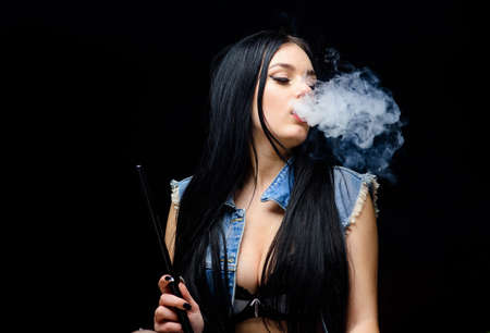 Relaxing with hookah. Nicotine addiction. Attractive busty brunette smoking vaping device. Girl...