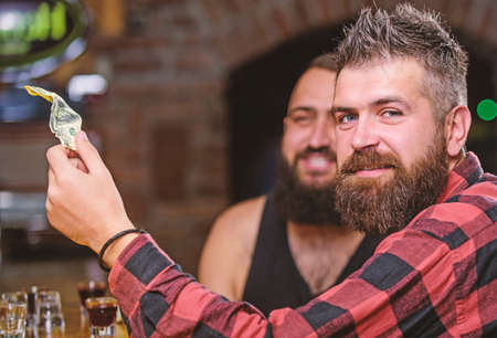 Hipster brutal bearded man spend leisure with friend at bar counter. Order drinks at bar counter. Men relaxing at bar. Friendship and leisure. Friday relaxation in bar. Friends relaxing in pubの写真素材
