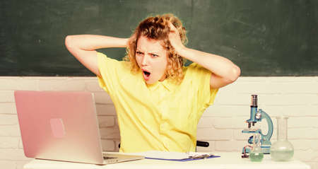 worried student with microscope and beaker. girl in classroom laboratory with computer. biology...