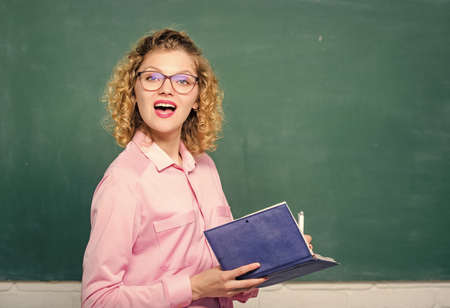 Passionate about knowledge. Pedagogue hold book and explaining information. Education concept. Teacher explain hard topic. Teacher best friend of learners. Woman school teacher in front of chalkboardの写真素材