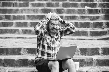 It is unbelievable. Escaped of office. successful entrepreneur. shocked man sit on stairs with laptop and checking email. Freelancer man work on computer. Businessman use notebook. take away coffeeの写真素材