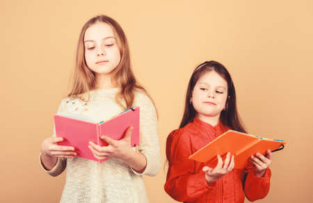 Sisters pick books to read together. Adorable girls love books. Secret diary. Opening doors through literacy. Kids girls with books or notepads. Education and kids literature. Favorite fairytaleの写真素材
