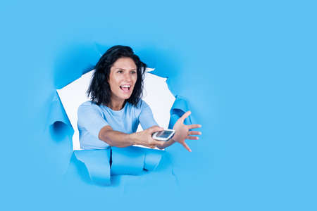 girl on blue background. feeling unhappy about news. student girl use remote control. portrait young...