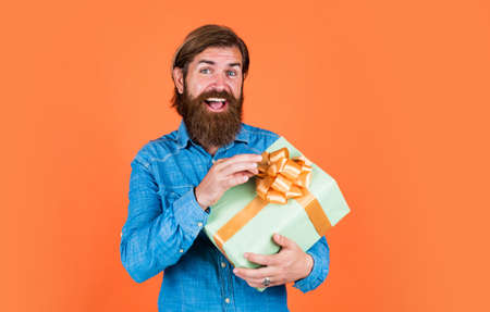 mature man with beard and trendy hairstyle hold gift box, discount