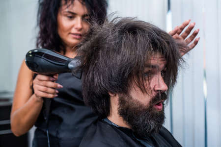 mature hipster with beard at hairdresser. brutal hipster with moustache wash hair before new hairstyle. barbershop. male trendy hairdo. perfect haircut. barber master blow dry hairの写真素材