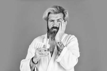 having toothache. bearded hipster relax in bed. he need bed rest. consequences of hangover. man take pill against insomnia. have terrible headache. male health remedy. healthy lifestyle conceptの写真素材