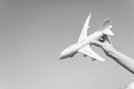 Plane model in hand. Airplane on blue sky. Jet or aircraft toy on sunny outdoor. Travel by air transport, aviation. Symbol of wanderlust, trip and vacation. Dream and imagination concept, copy spaceの写真素材