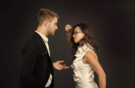 Angry professional woman clench fist at male coworker in formalwear dark background, fightingの写真素材