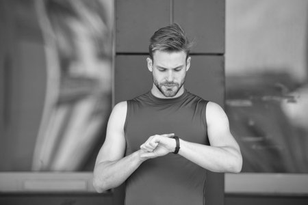 Set up route. Man athlete busy face check fitness tracker urban background. Athlete with bristle...