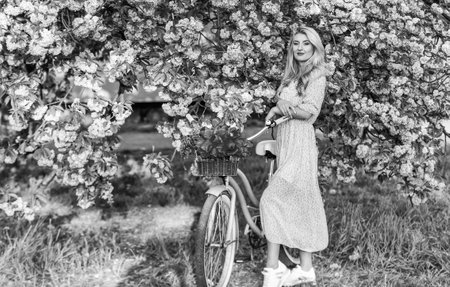 Girl casual dress retro cruiser bicycle sakura tree. Spring holidays. Tourism concept. Transportation and travel. Sakura season. Flora and botany. Woman with tulips bouquet. Sakura tree bloomingの写真素材