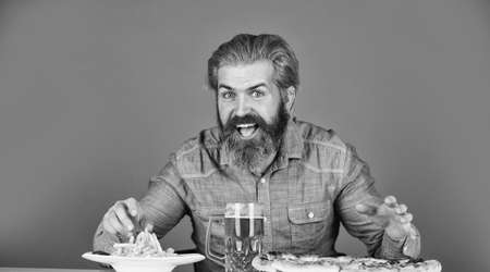 Enjoy your meal. Beer and food. Dinner at pub. Hungry man drink beer and eat snacks. Bar restaurant. Cheerful man bearded hipster drinking beer. Friday party concept. Good appetite. Consume alcoholの写真素材