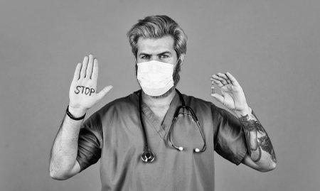 Open palm stop gesture. Epidemic threshold. Man in medical lab. Protective mask. Stop epidemic. Virus concept. Danger zone. Epidemic infection. Critical number or density of susceptible hostsの写真素材