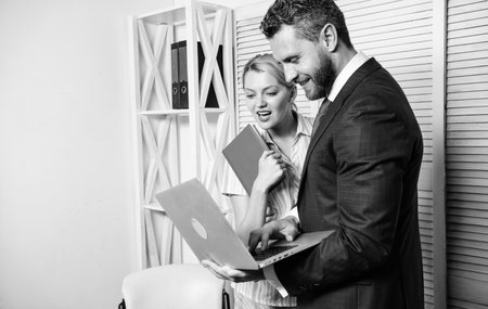 Office business partner show information data statistics online. Boss and secretary or assistant work as team. Ask opinion of colleague. Businessman hold laptop surfing internet with colleagueの写真素材