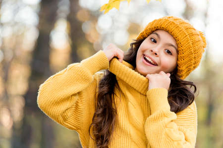 Fresh air and good mood. fall fashion for kids. autumn style of child. knitwear warm you in any weather. girl in knitted sweater and hat. kid enjoy nature in autumn park. fall is a time for funの写真素材