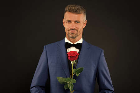 Lovely face of male. groom in tuxedo with rose. during wedding ceremony. groom in wedding jacket. bowtie is principal element for men. fashionable man with flower. groom man in suit. elegant boyの写真素材