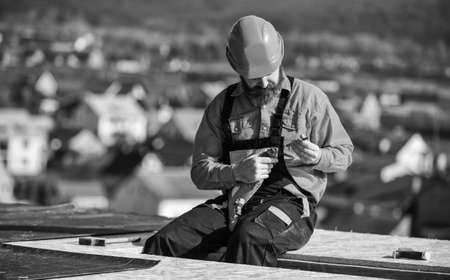 Install vapor barriers or layers of insulation on flat roofs. Roofer constructing roof. Master repair roof. Flat roof installation. Man hard hat working outdoor landscape background. Building houseの写真素材