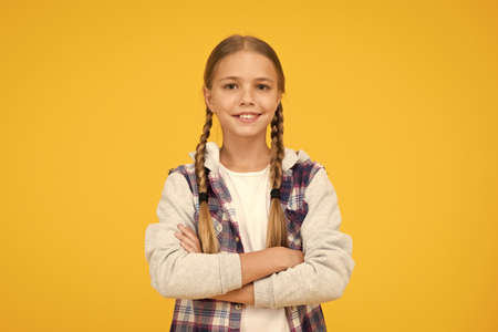 Casual style. Little girl yellow background. Good mood concept. Positive vibes. Self confidence. Cute braided girl. Kid long hair. Small girl checkered shirt. Happy international childrens dayの写真素材