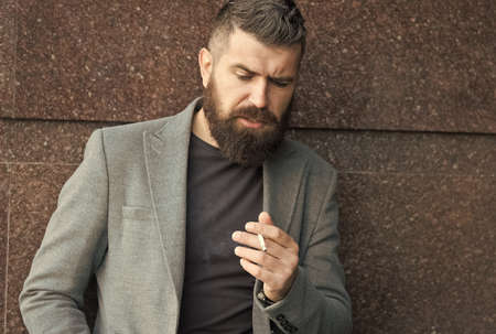In his own style. charismatic business man smoking outdoor. bearded man smoke cigarette. brutal...