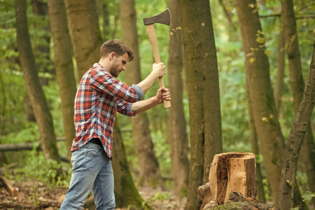 Force is required. survive in wild nature concept. man with axe in the forest. cutter going to cut tree. lumberjack holding ax in hands. wanderlust, hiking and travel. tree cutter with axeの写真素材