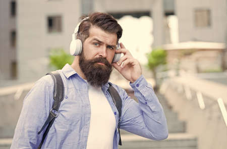 Live life loud with headphones. Hipster wear headphones outdoors. Bearded man listen to music in headphones. New technology. Modern life. Headphones for listening closelyの写真素材