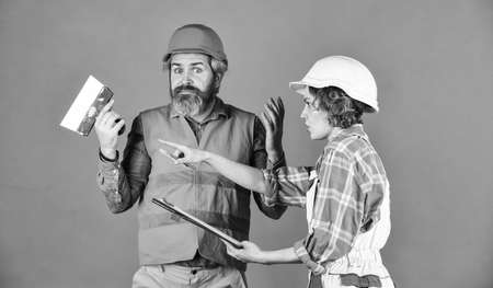 Couple planning changes renovation apartment. Sign contract with workers. Discussing renovation with contractor. Renovation concept. Price list. Couple look documents. Woman and man safety hard hatの写真素材
