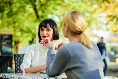 Friendship or rivalry. Girls friends drink coffee talk. Conversation of two women cafe terrace. Friendship friendly close relations. Revelation and support. Friendship meeting. Trustful communicationの写真素材