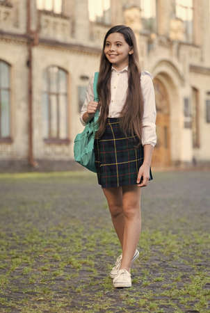 Little girl formal style uniform and backpack in school yard, public school concept