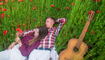 Cute couple. happy family. country music. spring nature beauty. love and romance. romantic relationship. couple in love with guitar. man and woman in poppy flower field. summer vacationの写真素材