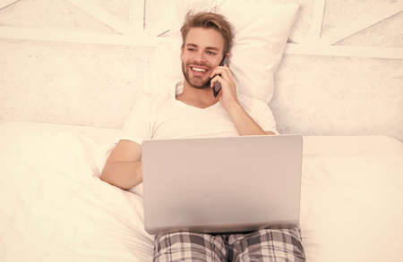 Enjoy the conversation. Happy man talk on cellphone in bed. Phone call. Telephone callの写真素材