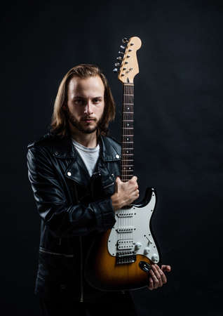 presenting product. string musical instrument. bearded rocker.