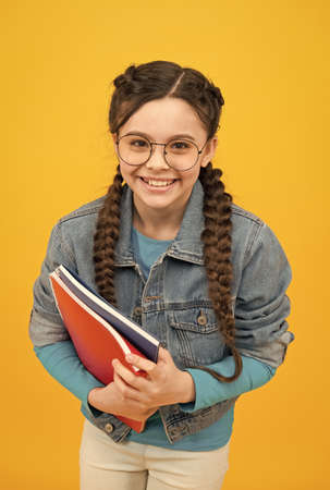 Happy kid with nerd look hold school books in casual fashion style yellow background, back to school