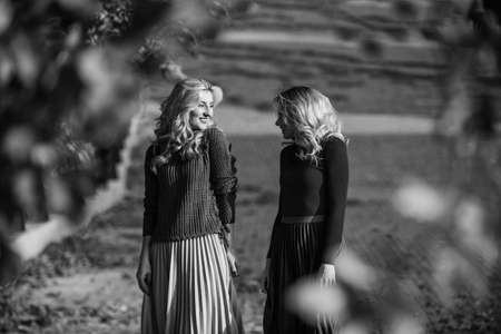 Femininity and tenderness. Women walking in autumn park. Pleated skirt fashion trend. Friends girls. Autumn stylish outfit. Fall fashion. Adorable ladies enjoy sunny autumn day. Fashionable clothesの写真素材