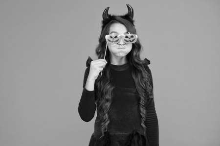 halloween child in suit and imp hors with pumpkin party glasses makes faces emotionally, halloween holidayの写真素材