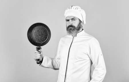 cuisine rich vitamins. preparing food in kitchen. husband in chef hat on kitchen. Cooking food concept. Hold frying pan. best quality. bearded cook in uniform with tools. bearded man hold cooking panの写真素材