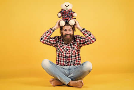 Caucasian mature hipster with trendy hairstyle in checkered shirt hold teddy bear toy, funの写真素材