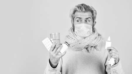 Prevention concept. Man sick leave at home. Bearded guy messy hair wear mask hold pills tablets vitamins medicines in hands. Medicines effective treatment. Pharmacy concept. Lot of medicinesの写真素材