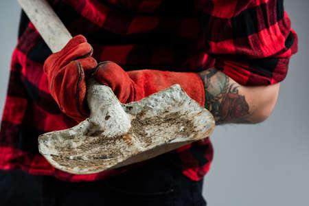 labor day. building and repairing. handsome man laborer. male worker in uniform with shovelの写真素材