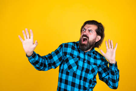 emotional man on yellow background. brutal bearded hipster. mature guy with moustache on face. expressing human emotions. angry man in checkered shirt. he is afraidの写真素材
